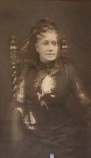 Woman wearing mourning clothes seated in an ornate chair.