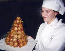 A professional pastry chef presents a French croquembouche.