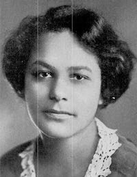 Photo ancienne : portrait en noir et blanc d'une jeune femme noire arborant un chemisier à dentelle, les cheveux ondulés noirs et courts.