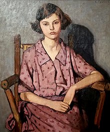 Girl in a dotted dress sitting in a chair.
