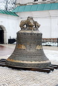 Cloche devant la porte-église de la Trinité.