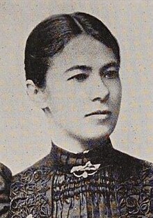 Portrait of a woman with her hair pulled back wearing a high-collared dress with elaborate rutching