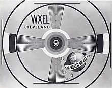 Television text pattern slide in the monochrome "bullseye" test style. Inside the center is a numeric "9"; at top-left in two lines are "WXEL" and "CLEVELAND"; at bottom-right is a globe with a band in the middle, reading "THE WORLD ON VIEW"