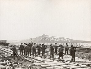 Från Riksgränsbanans bygge år 1900. Rälsläggarlag vid Luossavaara, som samhället Kiruna då kallades. Dit hade banan hunnit i juni det året. I bakgrunden fjället Kirunavaara med ännu av sprängskotten oförändrad kontur. Högsta toppen, "Statsrådet", sprängdes bort fem år senare.