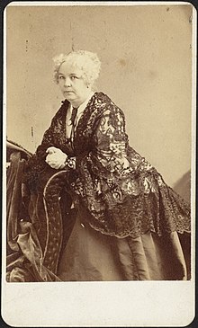 Photograph of Elizabeth Cady Stanton leaning on a piece of furniture and turning toward the camera