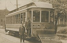 Erie Western Electric Railway car in Toledo, Ohio with one man standing in the entrance to the car while another stands on the ground next to the car.