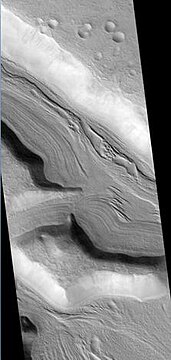 Clanis and Hypsas Valles, as seen by HiRISE. Ridges are probably due to glacial flow. Ice is covered by a thin layer of rocks. Location is Ismenius Lacus quadrangle.