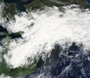A satellite image of an extended area of clouds oriented southwest to northeast across the Great Lakes region of the United States and Canada