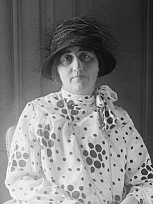 Woman wearing a white dress with large black polka dots and a cloche hat