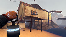 An image from Ether One's gameplay shows the player character's view from a first-person perspective. We see his hand holding a lantern, as he comes upon a dilapidated white brick house along the water. Cliffs are visible in the background.