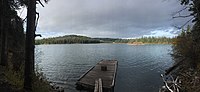 A small lake with the far side visible and the dirt shore in the foreground