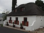 Free-standing extensively altered single storey cottage with attic; full hipped thatched roof; sash windows with leaded lights and solid shutters; double casement dormer windows; all joinery unpainted and appears to be modern stock; raised stoep with end Type of site: House Current use: House.