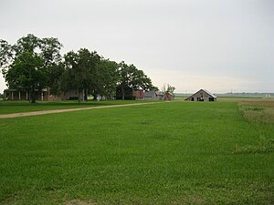 The view is south toward the Heard-Northington Plantation on FM 1161 in Egypt. The road beyond the barn is FM 102.