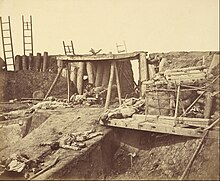 The interior of an earthen and wooden fort with dead bodies scattered around it