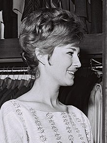A smiling woman in profile, with a bouffant hairstyle.