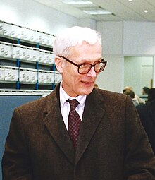 An older white man in a formal coat and tie