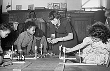 Children and one woman seated on floor with models representing roads.