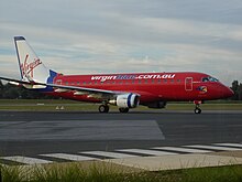 Mostly-red aircraft, with white fin and blue letterings, on ramp