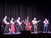 Sutton (second from right) playing guitar in 2022, in support of Bela Fleck's album My Bluegrass Heart.
