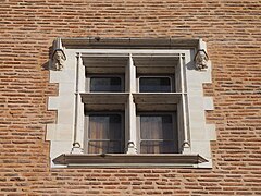 Photographie en couleur d'une fenêtre d'un bâtiment en briques rouges.