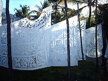 embroidered tablecloths hang on lines from palm trees