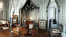 Frederick I's bedroom, laid out in a Neoclassical style, with walls draped with silver silk. Two marble statues (left and right) flank the alcove containing the king's bed (center).