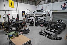 The Eurospares cars dismantling workshop with two cars on the ramp and one black Lamborghini with front bumper and parts on the floor.