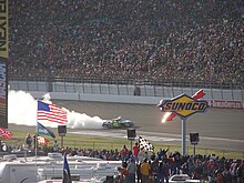 Jimmie Johnson performing a burnout to celebrate a race victory on the edge of a banked turn