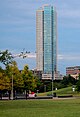 Ground view from the south of a 43-story tower. The building has a green glass facade on the right side, and a solid brick side with windows on the left.