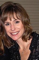 Smiling woman with medium-length brown hair, dressed in dark clothing.