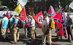 Men stand in the street holding Confederate, Nazi, and Gadsden flags.