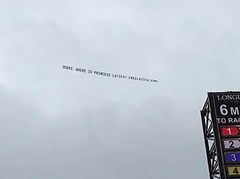 Top left corner of the video board at Churchill Downs, above it a banner against a cloudy sky, reading: DUBAI, WHERE IS PRINCESS LATIFA? FREELATIFA.COM