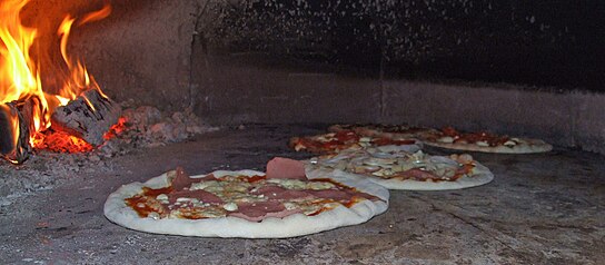 Pizzas baking in a traditional wood-fired brick oven