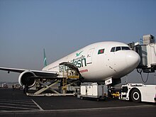 A white aircraft with cargo doors open being loaded.