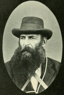 Black and white portrait of a middle-aged man with a beard and hat