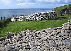 The fence marks the line of the top of the cliffs showing where parts of this promontory fort have fallen into the sea.