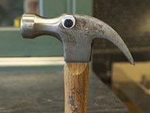 One googly eye attached to the side of the metal piece of a hammer