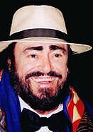 Pavarotti in a black bowtie, a white brimmed hat, a colourful scarf and a big smile.