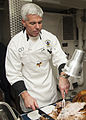 Capt. Karl Thomas, commanding officer of the Nimitz-class aircraft carrier USS Carl Vinson, serves food on the mess decks during Thanksgiving dinner on 27 November 2014. Carl Vinson was deployed in the U.S. 5th Fleet area of responsibility supporting Operation Inherent Resolve, strike operations in Iraq and Syria as directed, maritime security operations, and theater security cooperation efforts in the region.