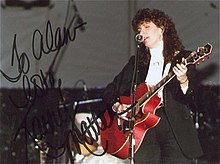An autographed photo of singer Kathy Mattea, playing a red guitar and singing into a microphone