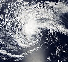 A photograph of a tropical depression over the Eastern Pacific Ocean. Convection associated with the depression is fairly light and mostly confined to the top-left quadrant, with the center of circulation being nearly outside of the convective canopy. A long, broken rainband extends eastward from the northern flank of the depression. A large expanse of wispy, puffy, high clouds surrounds the depression to the top-right, top-left, and bottom-left.