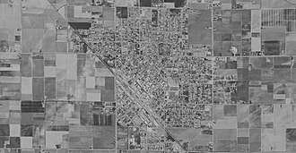A low-contrast black-and-white satellite image of a small city and surrounding farm land