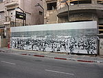 צילום היסטורי של חוף ימה של תל אביב, המוצג על הגדר המקיפה בית בבנייה ברחוב הירקון