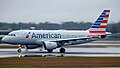 An American Airlines Airbus A319 speeds down Runway 17 before taking off at MHT during rainy weather.