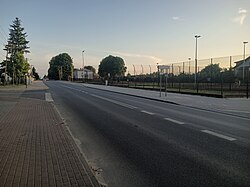 Główna Street, main street of the village. Bus stops of public transport from Tomaszów Mazowiecki in the background, then a primary school.