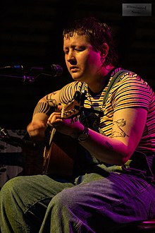 Sternberg playing guitar, seated