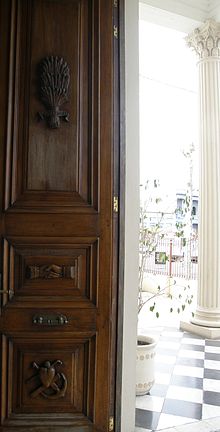 Detalles tallados en la puerta de entrada al Museo Solari de Fray Bentos, con elementos simbólicos de la Sociedad Cosmopolita de Socorros Mutuos