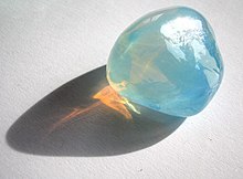 A piece of blue-looking opalescent glass, with orange light glowing in its shadow