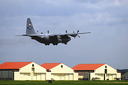 A C-130 Hercules aircraft of the 908th Airlift Wing takes off from Maxwell Air Force Base with the wing's maintenance hangars in the background.