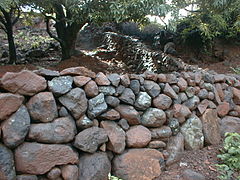 Mur de blocs arrondis empilés, de hauteur décroissante depuis la base ; les deux faces accusent un fruit marqué ; San Ramon, Choluteca (Honduras).